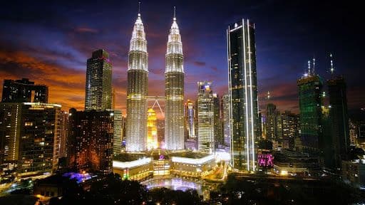 Kuala Lumpur skyline at night with Petronas Twin Towers illuminated.